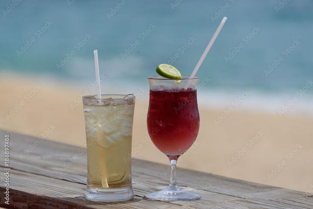 Two iced alcoholic beverages, in frosty glasses, with beach and surf in background. Two iced alcoholic beverages, in frosty glasses, with beach and surf in background.