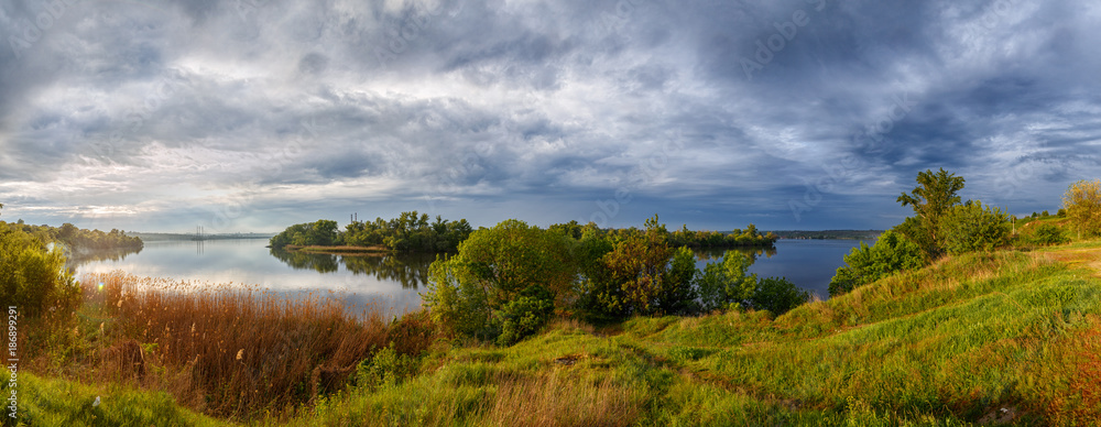 Bright colors of nature. The Dnieper river bank. Overcast sky. Panorama.