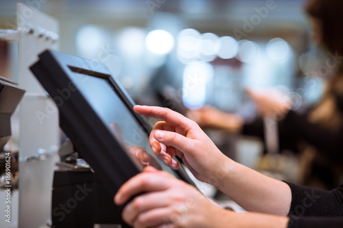 Young woman hand doing process payment on a touchscreen cash register, finance concept (color toned image) © Khaligo