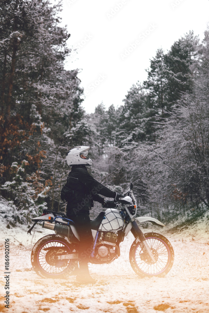 Rider man on a motorcycle Winter motocross. Skid on a snowy forest. the snow from under the wheels of a motorcycle Enduro. off road dual sport travel tour, active life style concept vertical