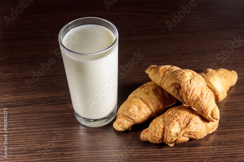 Glass of milk and fresh croissants on wooden table