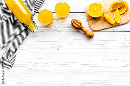 Make orange juice. Juicer, beverage in bottle and glasses near slices of oranges on white wooden background top view copyspace