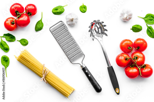 Cooking italian pasta. Spaghetti, tomatoes, garlic, basil and cookware on white background top view