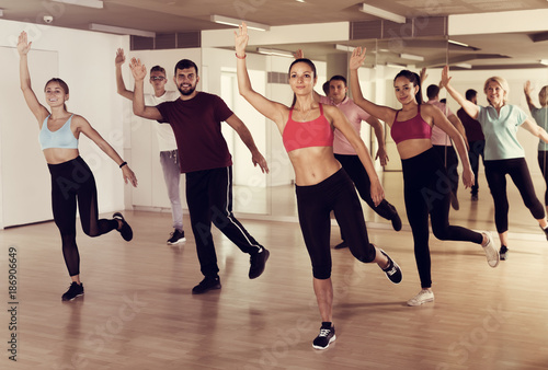 Group of active people training dance in studio
