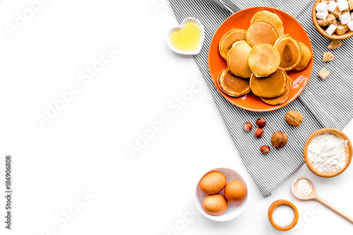 Cooking american pancakes. Ingredients, cakes, nuts and honey on white background top view copyspace photo