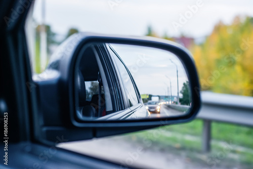 the reflection of the road with cars in the rearview mirror car traffic in the evening background backdrop