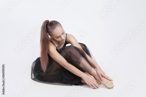 Dancer in in tutu sitting on floor, touching her foot