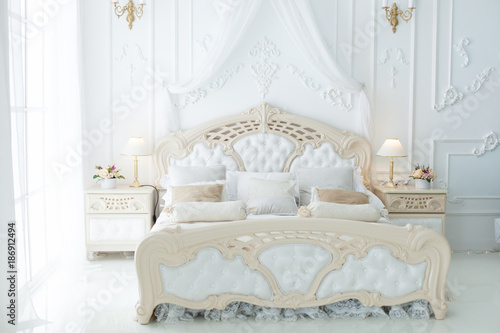 Bed in a large beautiful bedroom in the style of rococo.