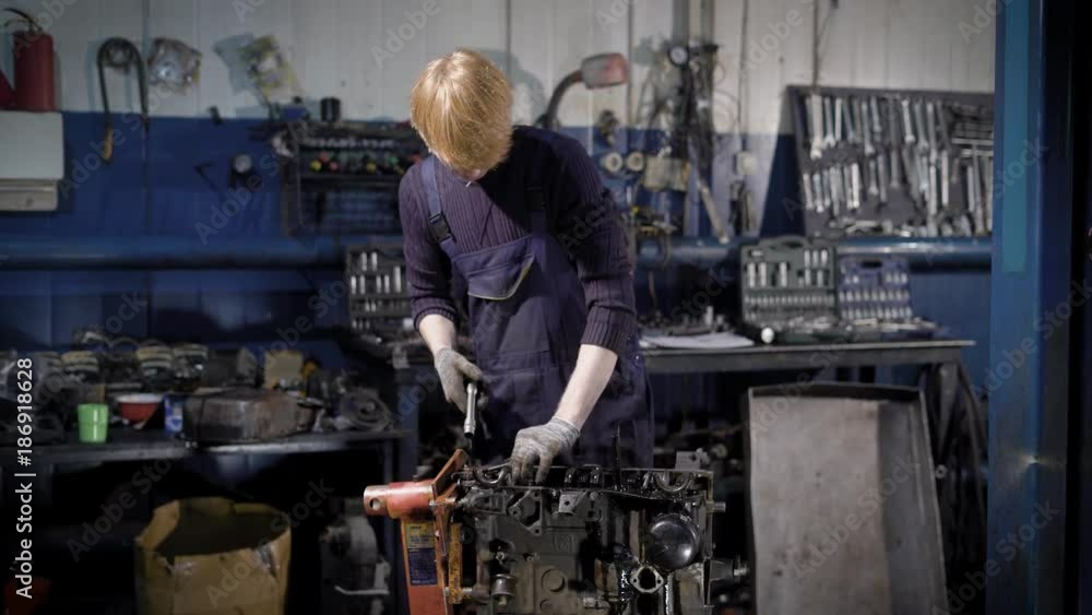 Young technician using tools and servicing engine in garage Young technician using tools and servicing engine in garage