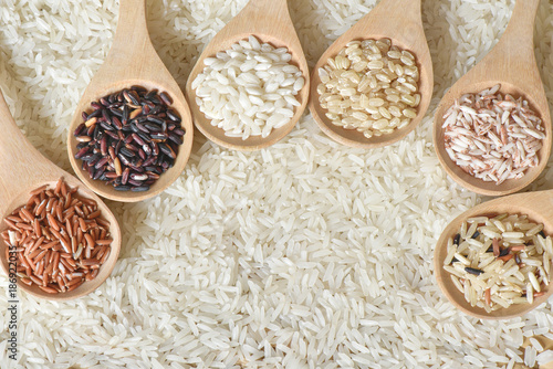 Top view different rice on wooden scoop with jasmine rice background, Various rice organic on wooden spoon collection