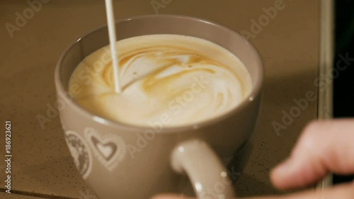 pouring stream milk into a cup of coffi photo