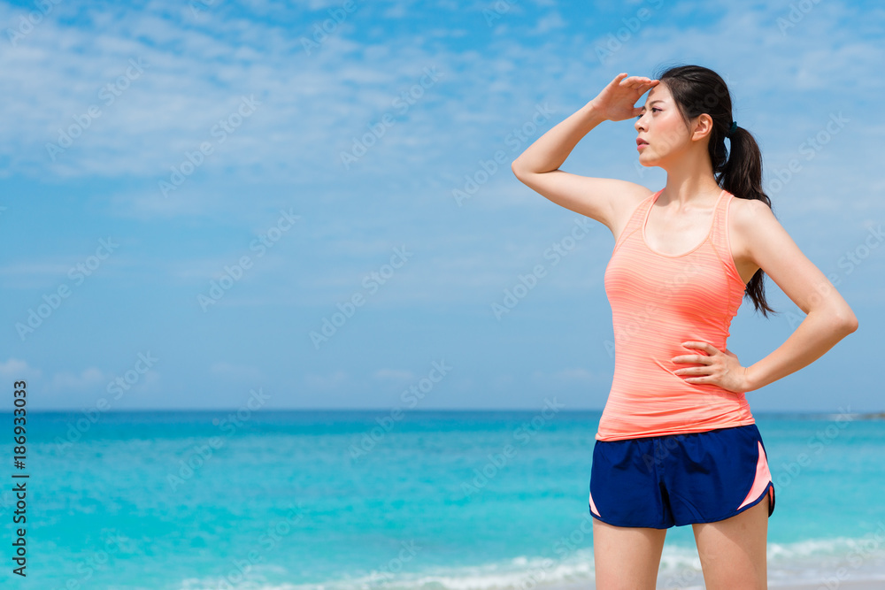 beautiful female fitness runner standing on beach