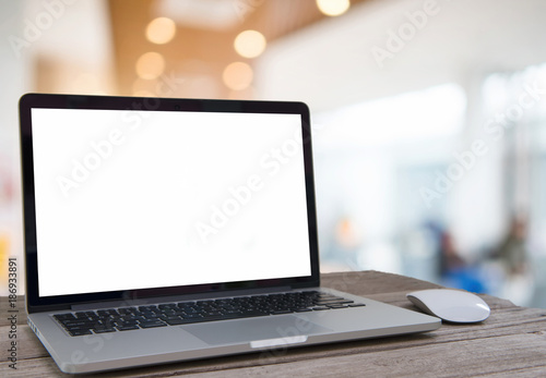 Laptop with blank screen on table of coffee shop blur background with bokeh.