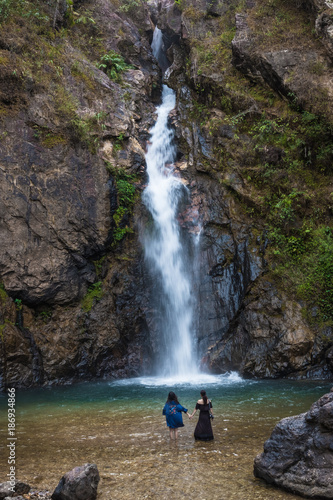 Two women standing in a waterfall.
