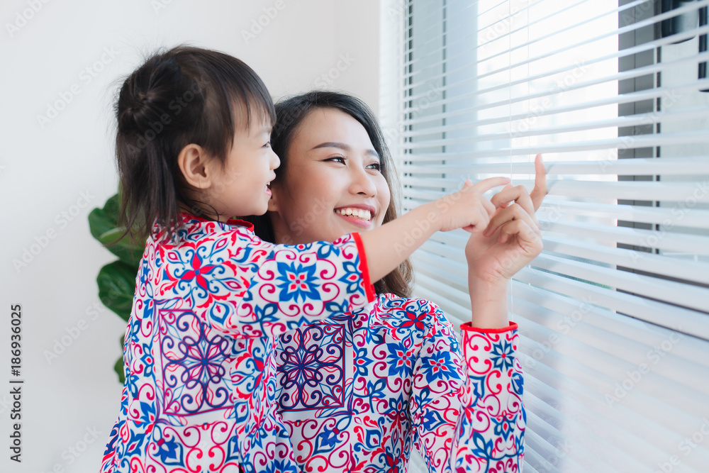Vietnamese mother and daughter in Ao Dai Traditional dress, celebrate new year at home. Tet Holiday.