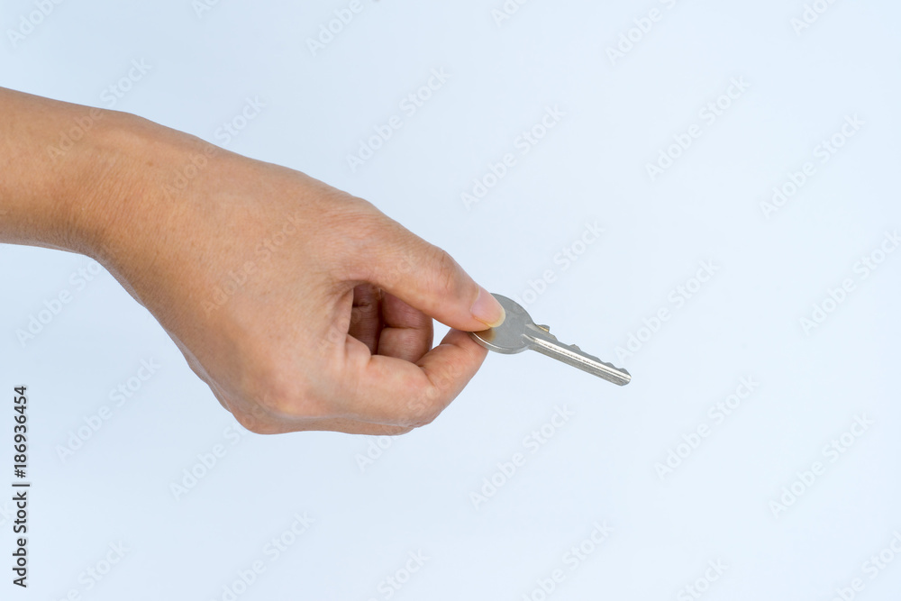 Female hand holding metal key with thumb and index finger Female hand holding metal key with thumb and index finger
