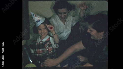 1953 Young girl wearing birthday hat opens present
