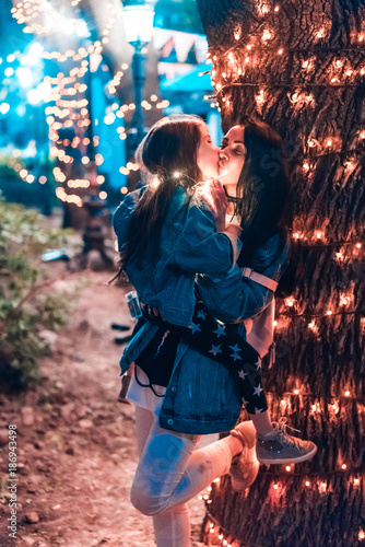 mom kisses her daughter in the evening park