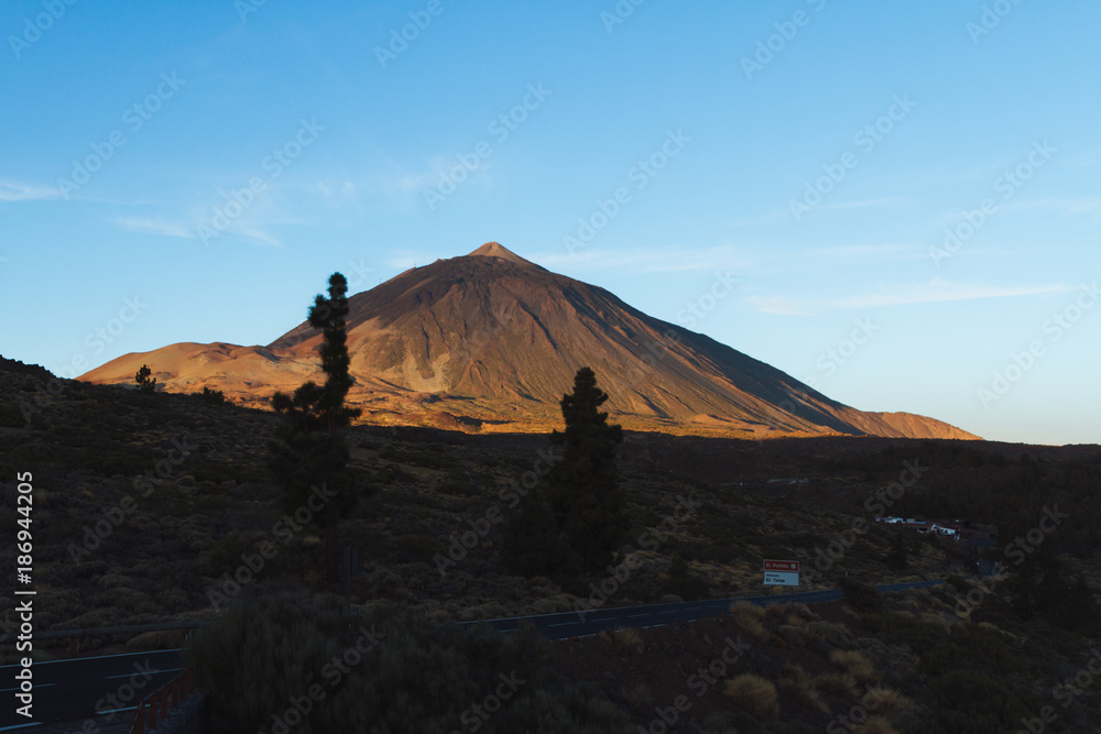 Orange sunrise light on volcano in desert landscape