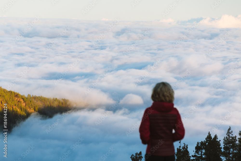 Young woman above cloud inversion in desert landscape while sunrise Young woman above cloud inversion in desert landscape while sunrise