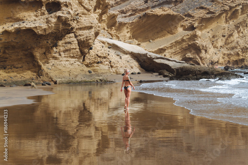 Young girl in bikini posing on sand beach in desert