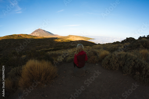 Woman looking at sunrise light on volcano in desert landscape