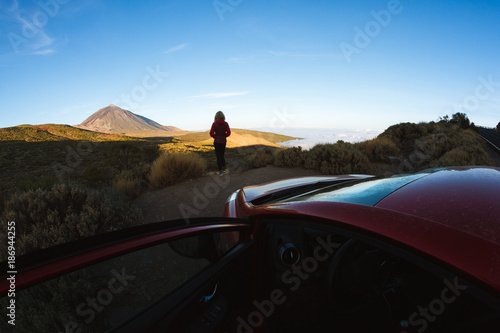 Woman looking at sunrise light on volcano in desert landscape
