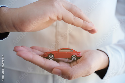 Concept of car insurance with Protection of a car. toy car and hand Business concept