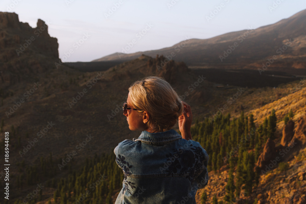 Girl in  jeans jacket looking at sunset in desert nature
