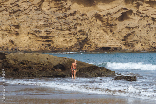 Young blonde girl in thongs posing on sand beach in desert