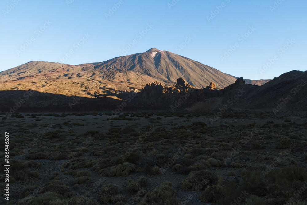Sunrise light on volcano in desert landscape