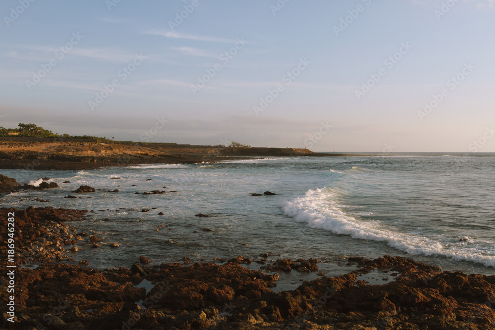 Surfers on ocean waves breaking on shore at dawn Surfers on ocean waves breaking on shore at dawn