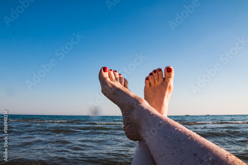Female feet and sea wave on a summer