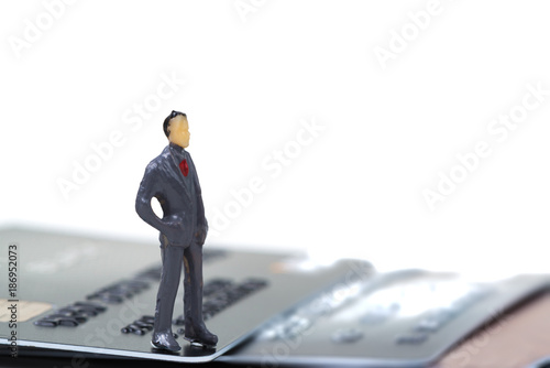 Figure miniature businessman or small people standing with stack of credit card on white background for money and shopping concept.