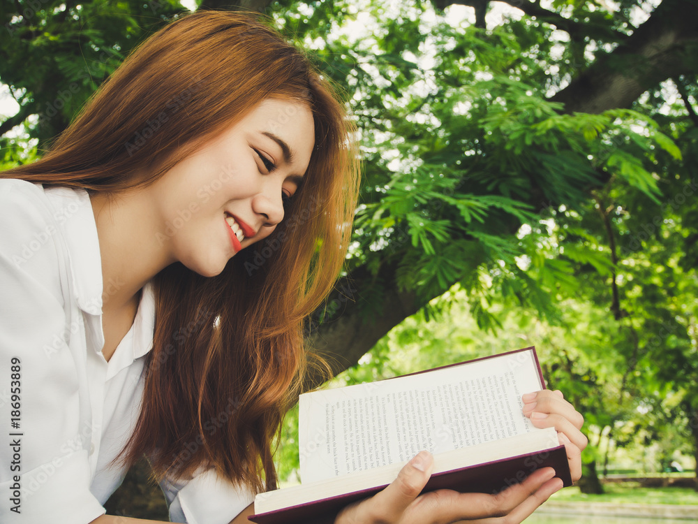 Obraz premium Young woman reading book at the park.