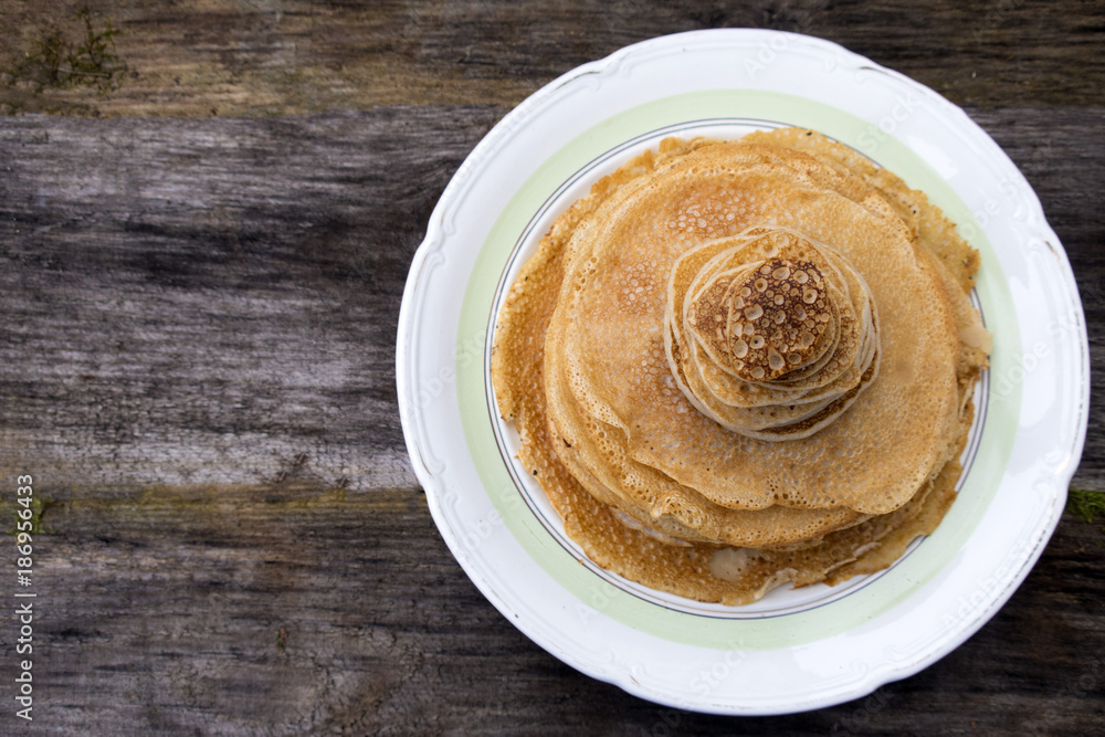 Large and small pancakes located on an old wooden table. Top view and space for copy space. Large and small pancakes located on an old wooden table. Top view and space for copy space.