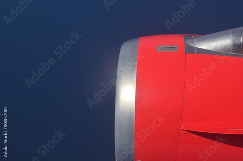 Close-up to an airplane engine against blue sky seen from the airplane during the flight