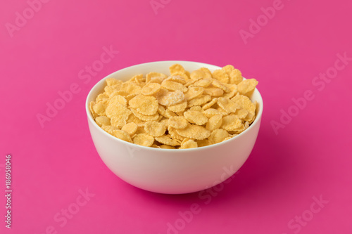 close-up view of white bowl with sweet tasty corn flakes isolated on pink