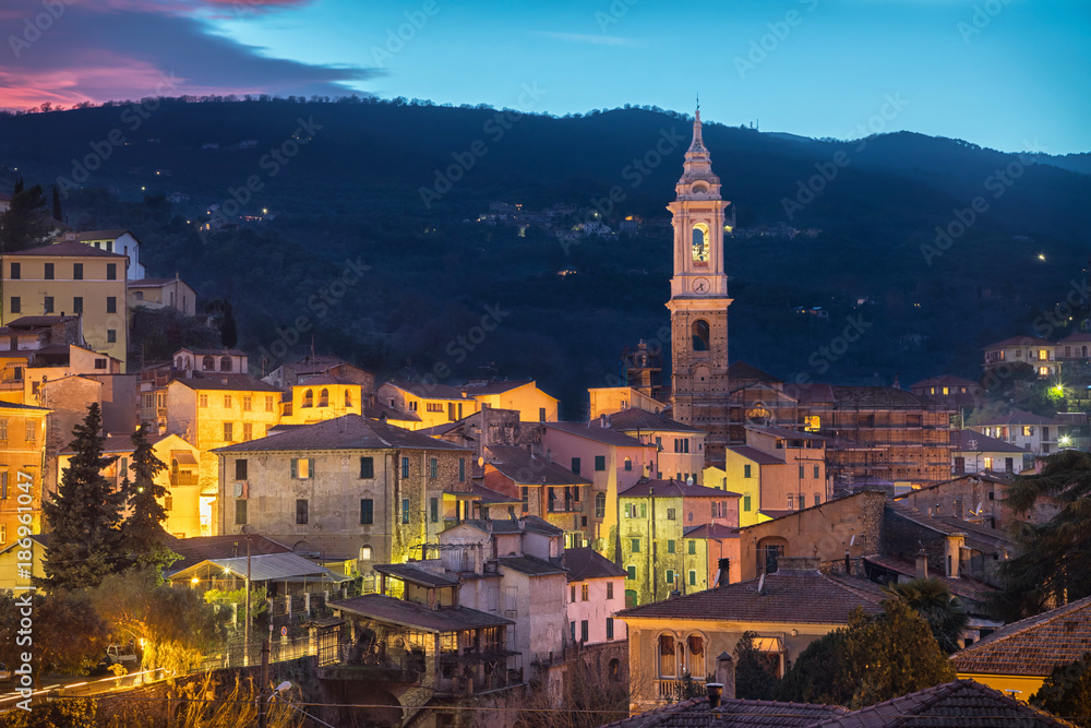 Obraz premium Cityscape of Dolcedo at dusk - small town located in Ligurian Alps, Italy. The main landmark is the bell tower of Church of Saint Thomas (Chiesa di San Tommaso)
