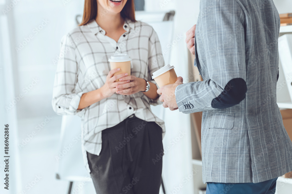 cropped image of male and female colleagues having coffee break in office