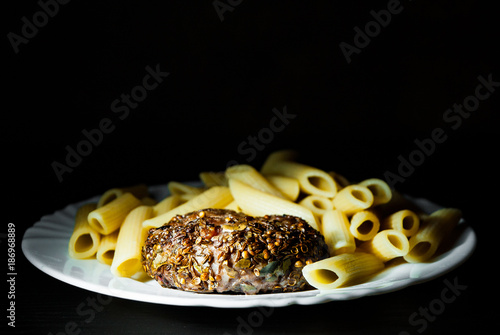 beef meat burger steak cutlets beefsteack with penne pasta on white plate on dark wooden background photo