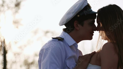 The close-up portrait of the boat captain kissing the girl during the sunset. photo