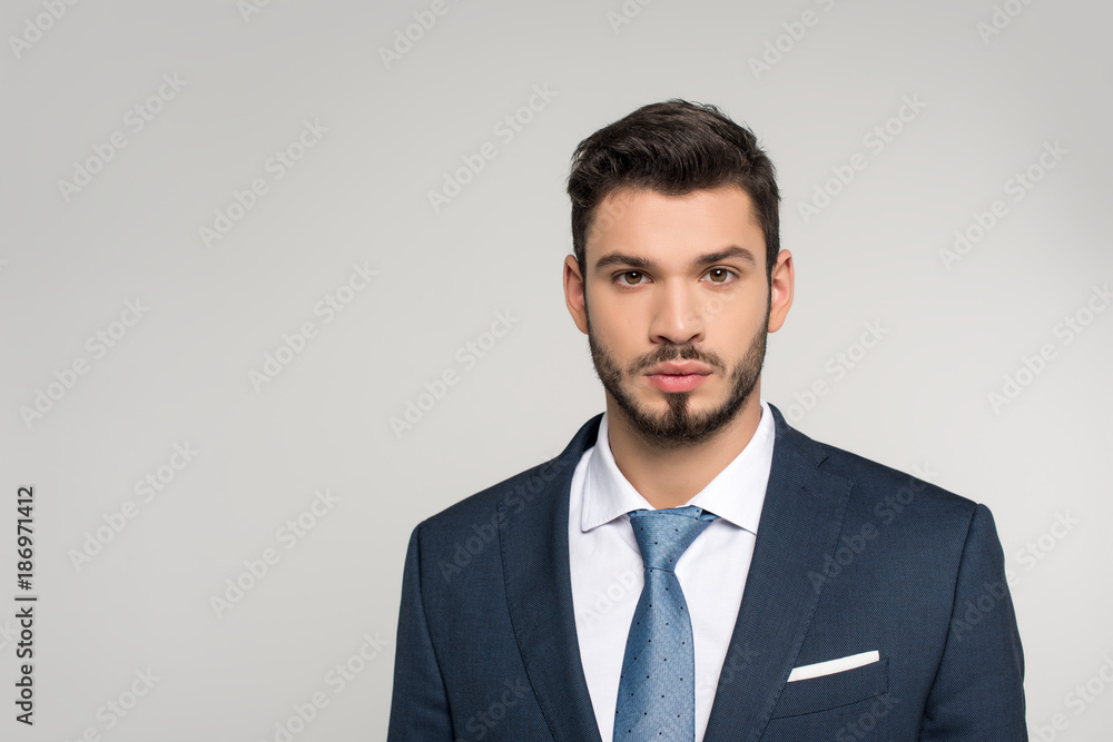 portrait of handsome young businessman looking at camera isolated on grey portrait of handsome young businessman looking at camera isolated on grey