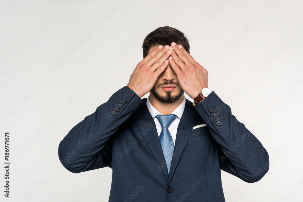 young businessman closing eyes with hands isolated on grey young businessman closing eyes with hands isolated on grey