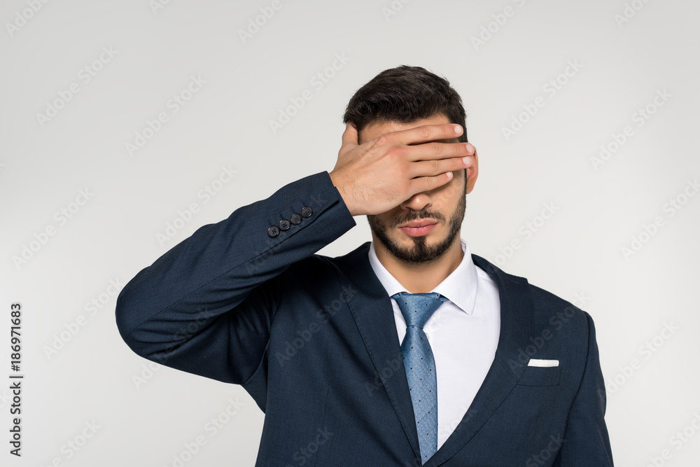 young businessman closing eyes with palm isolated on grey young businessman closing eyes with palm isolated on grey