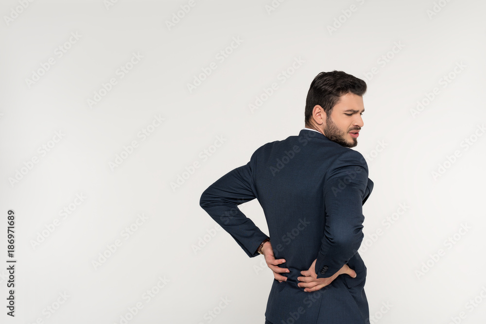 back view of young businessman suffering from backache isolated on grey back view of young businessman suffering from backache isolated on grey