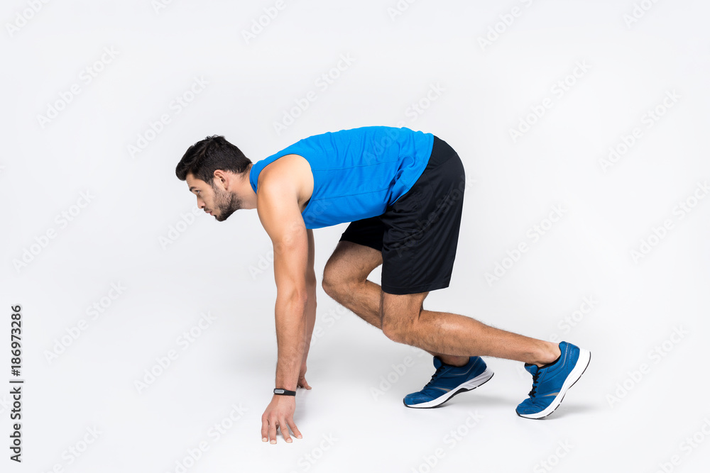 side view of young runner in start position on white side view of young runner in start position on white