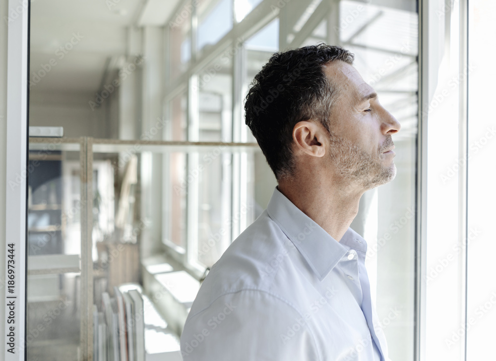 Businessman with closed eyes at the window Businessman with closed eyes at the window