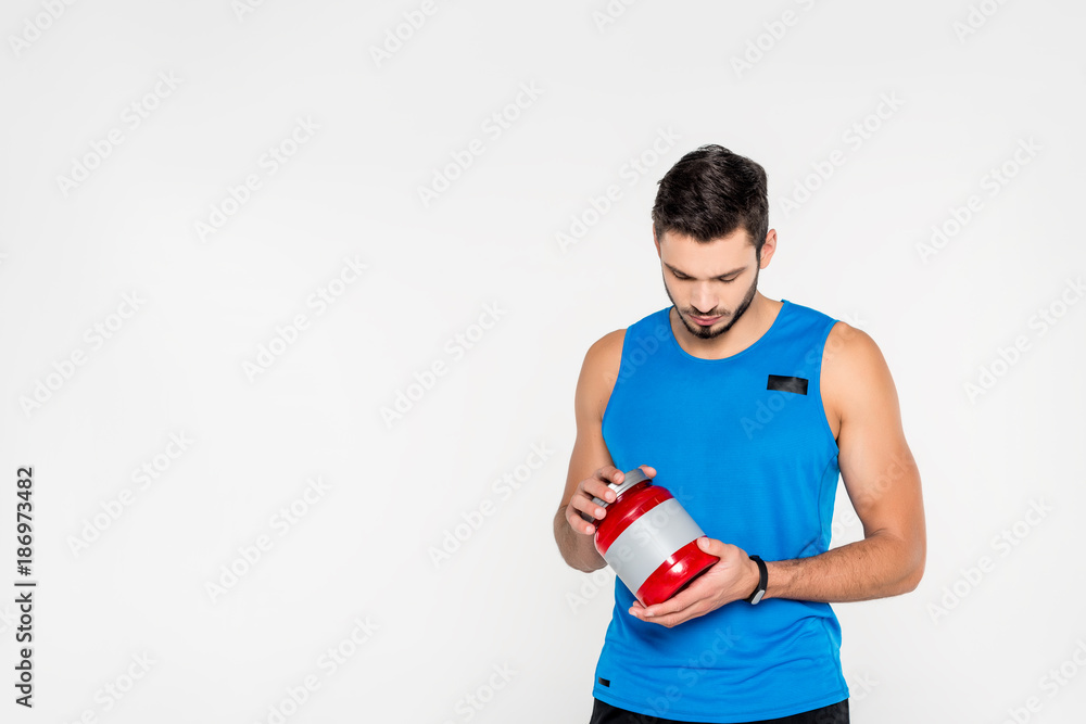 athletic young sportsman holding sport supplement jar isolated on white