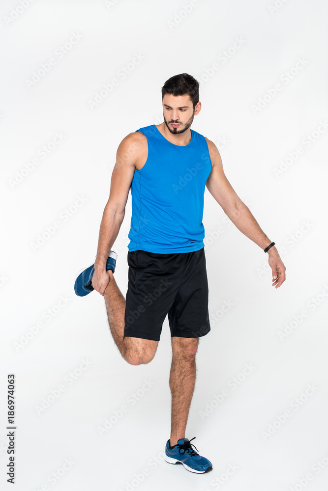 Obraz premium young jogger stretching leg before run isolated on white